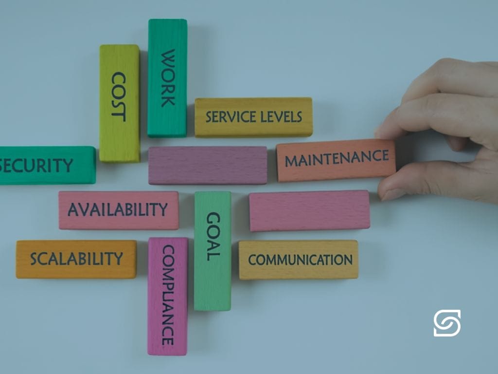 Colourful wooden blocks labelled with IT factors — security, cost, scalability, compliance, maintenance and communication.