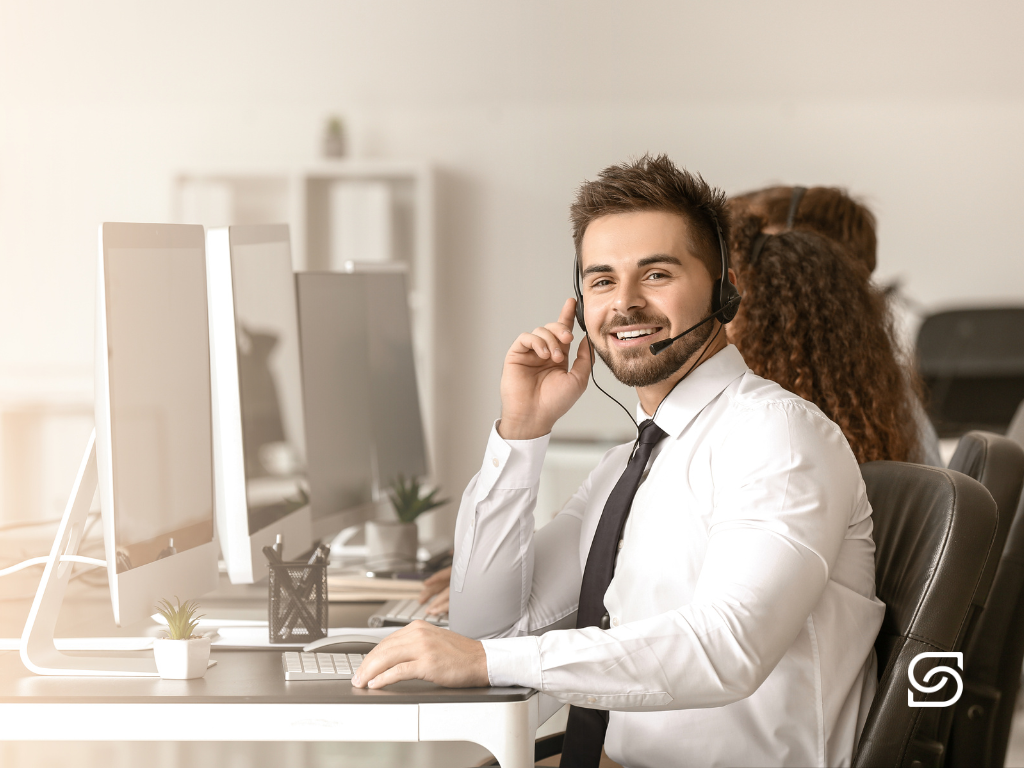 IT support representative working at a desk in a professional office environment.